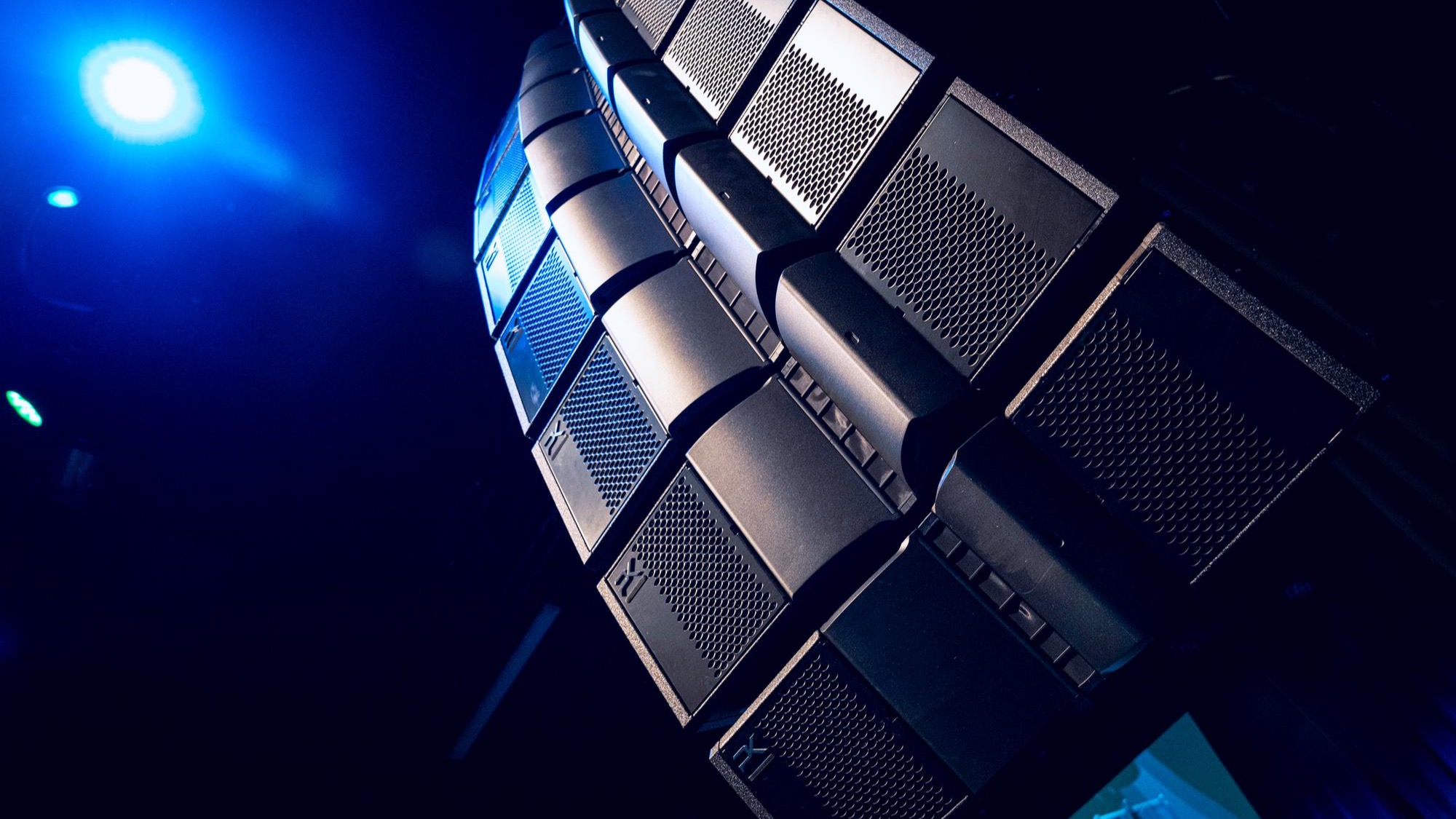 Close-up of a flown PK robotic line source array under blue stage light