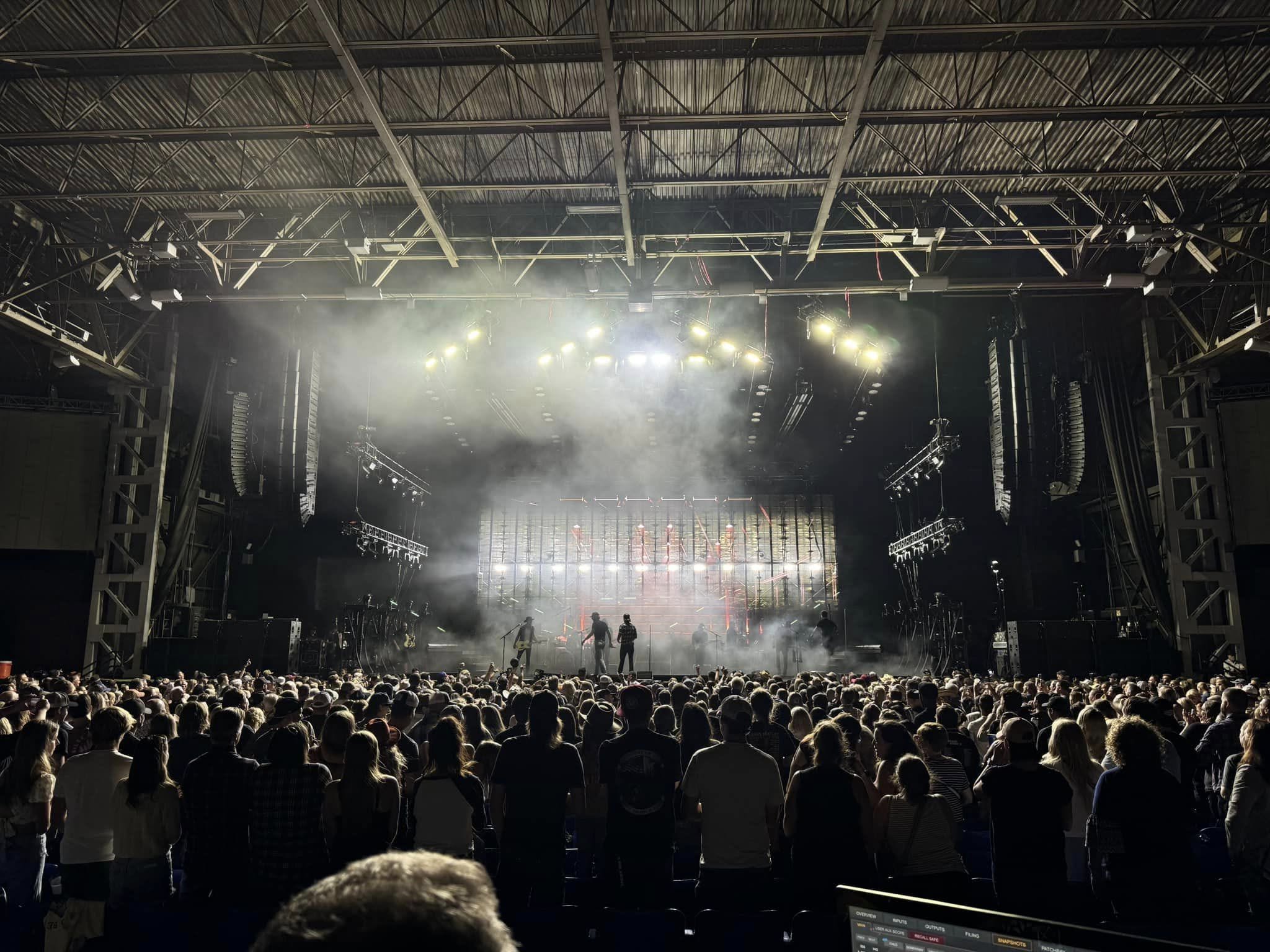 Dierks Bentley on stage beneath flown PK Sound arrays, seen from front of house